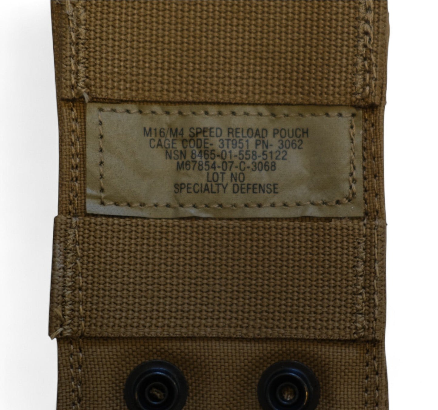 Close-up of the data placard on the M16/M4 Speed Reload Pouch, detailing the CAGE code (3T951), part number (PN-3062), NSN (8465-01-558-5122), and manufacturer information (Specialty Defense).